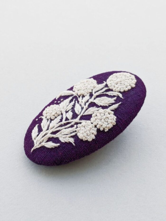 Détail broche en lin avec motif fleur brodé à l'aiguille