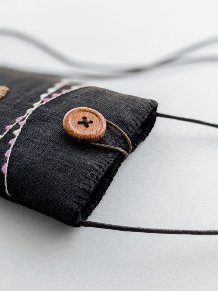 Détail pochette téléphone avec broderie et bouton bois